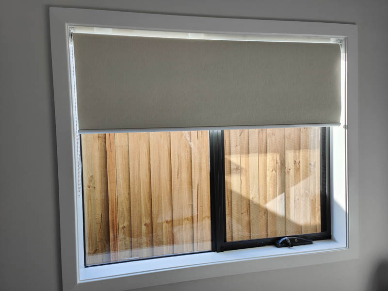Block-out roller blind drawn halfway down a window