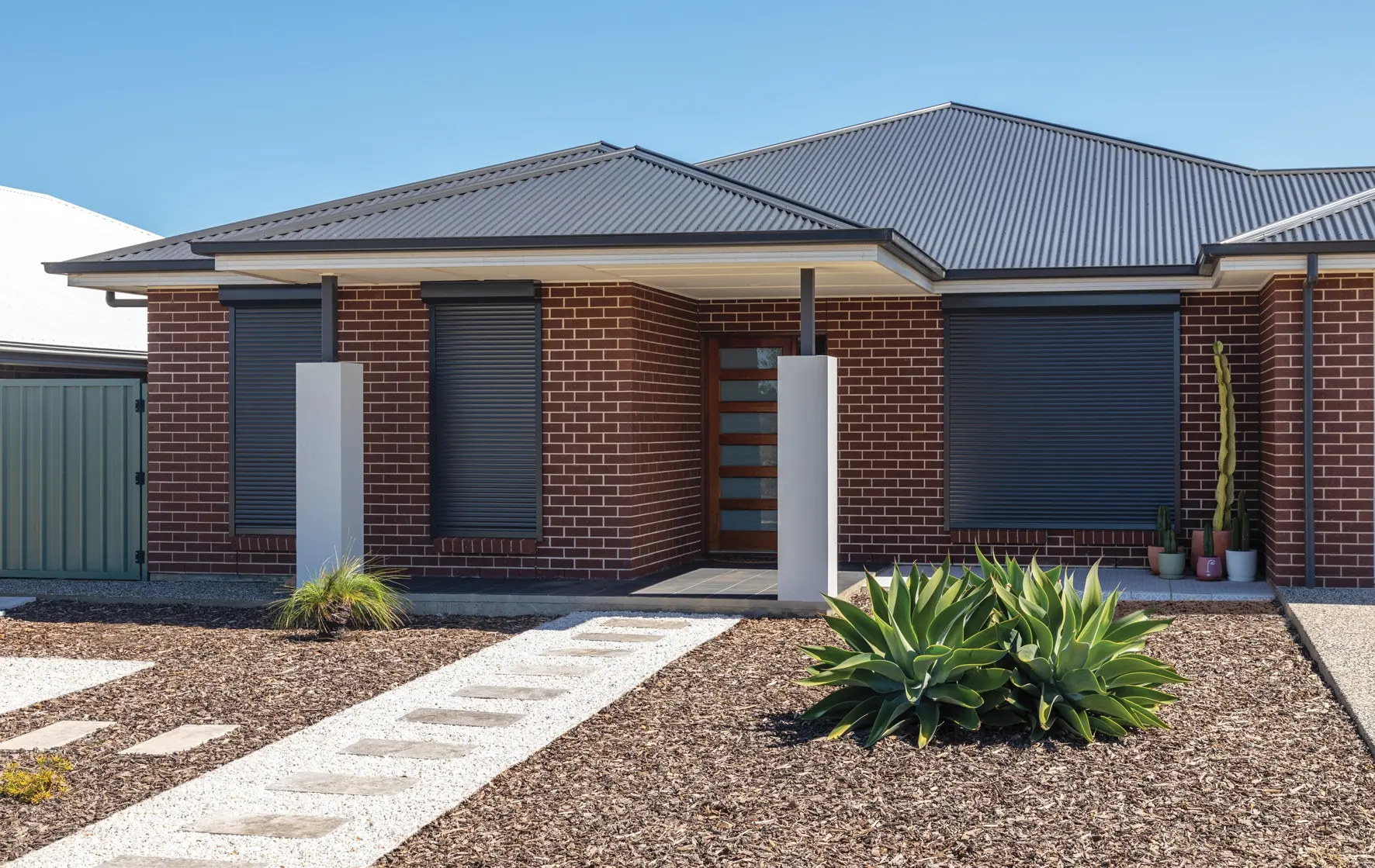 Charcoal roller shutters fitted across the front of a brick home