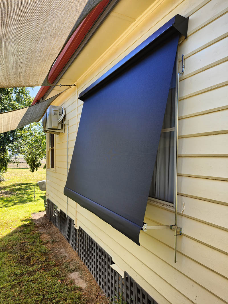 Close-up of a dark sunscreen sun blind and its bottom bar against weatherboard